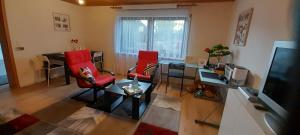a living room with two red chairs and a television at Ferien- und Business Wohnung in Mönsheim