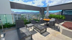a balcony with chairs and a table and an umbrella at Estadia tranquila e completa em prédio com piscina – VPD in Florianópolis