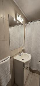 a white bathroom with a sink and a mirror at Departamento Paz in Tandil
