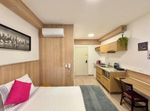 a bedroom with a large bed and a kitchen at Brooklyn Studios - Reservas Descomplicadas in Sao Paulo