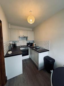 una cucina con armadietti bianchi e ripiani neri di Kirkgate Cottage - 2 Bedrooms - Sleeps 4 a Cockermouth