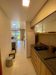 a kitchen with a white refrigerator and a table at Flat 06 CM - Frente Piscina in Tamandaré
