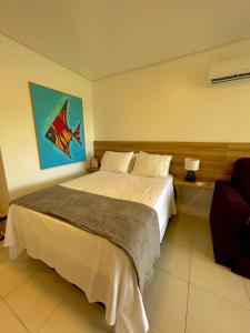 a bedroom with a bed and a painting on the wall at Flat 06 CM - Frente Piscina in Tamandaré +28 photos