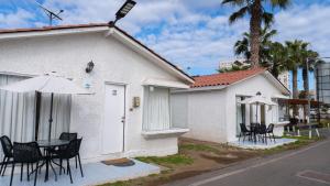 a white building with a table and chairs and an umbrella at Cabañas Pinamar in La Serena +24 photos