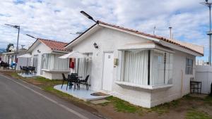 a white house with tables and chairs in a street at Cabañas Pinamar in La Serena