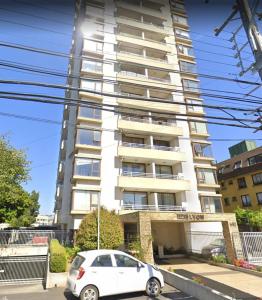 a white car parked in front of a tall building at Departamento Central para 7 personas con estacionamiento in Temuco +5 photos