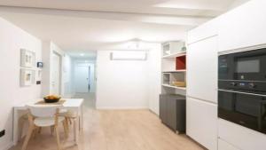 a white kitchen with a small table and a dining room at Apartamento Balears Navarra Ibiza in Ibiza Town