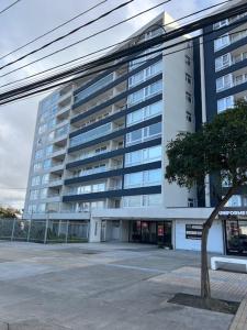 a tall building with a tree in front of it at Departamento Talcahuano Factura Empresas in Talcahuano
