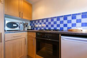 a kitchen with blue and white tiles on the wall at Loch Leven Loft in Milnathort
