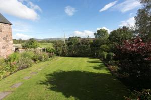 a garden with green grass and trees and a building at Loch Leven Loft in Milnathort