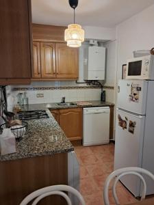 a kitchen with wooden cabinets and a white refrigerator at Can Vibru Vilallonga in Vilallonga de Ter