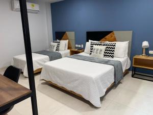 a bedroom with two beds and a blue wall at Kapital Suites in Pereira