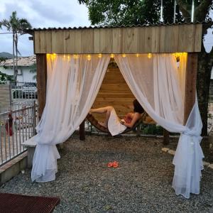 a woman laying in a hammock in a dog house at 06 Residencial Lazzaris a poucos metros do Beto Carrero in Penha +5 photos