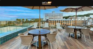 un balcone con 2 tavoli, sedie e ombrellone di Let's AX Fortune a Tambaú