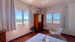 ein Schlafzimmer mit einem Bett und einem Stuhl und Fenstern in der Unterkunft Villa Torrecilla Sea View - South Costa, Nerja in Nerja