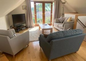 a living room with two couches and a tv at Loch Leven Loft in Milnathort