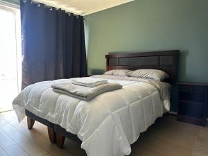 a bedroom with a bed with two towels on it at Espacio parque 1705 in Calama