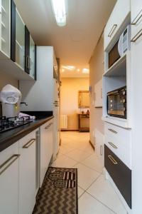 a kitchen with white cabinets and a microwave at Rosa Edificio Jardim dos Lagos in Canela