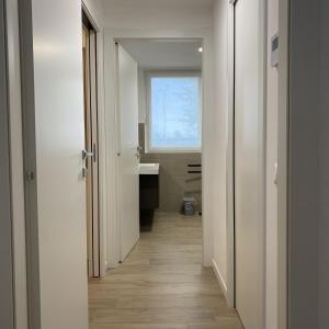 a hallway leading to a bathroom with a window at LuxuryApartmentBaiaBlanca Pool & Free Parking in Lido di Jesolo