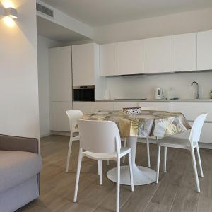 a kitchen with a table and chairs in a room at LuxuryApartmentBaiaBlanca Pool & Free Parking in Lido di Jesolo