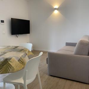 a living room with a couch and a table and a tv at LuxuryApartmentBaiaBlanca Pool & Free Parking in Lido di Jesolo