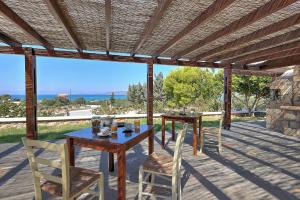 una mesa y sillas en un patio con vistas al océano en Psaromatis, en Elafonisos