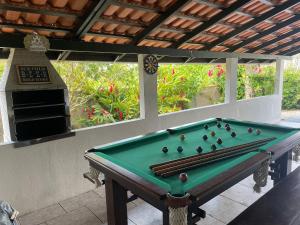 a pool table on a patio with an outdoor oven at Casa com PISCINA - 02 Quartos à 900m PRAIA e 3km do Beto Carrero - Estacionamento - Area de LAZER com Churrasqueira e SINUCA - Wi-Fi e Cozinha Completa in São Lídio