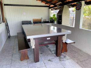 a large wooden table in a kitchen with a counter at Casa com PISCINA - 02 Quartos à 900m PRAIA e 3km do Beto Carrero - Estacionamento - Area de LAZER com Churrasqueira e SINUCA - Wi-Fi e Cozinha Completa in São Lídio