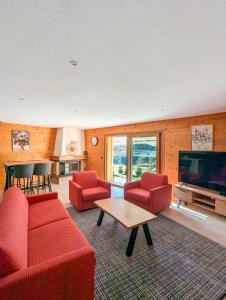 a living room with red furniture and a flat screen tv at Spacieux appartement Morgins cheminée, terrasse et jardin in Morgins