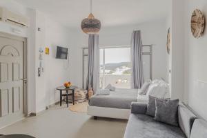 a bedroom with a bed and a couch and a window at Merichas Sea View Suites in Kithnos