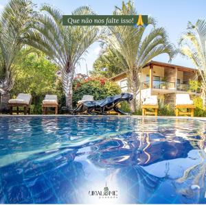 a swimming pool in front of a house with palm trees at Unalome Pousada in Serra Negra