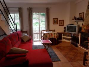 a living room with a red couch and a television at El Bosque Rural House in El Bosque