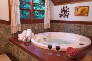 a bathroom with a tub with two glasses of wine at Pousada Recanto do Pinheirão in Visconde De Maua