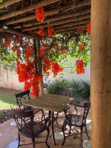 einen Tisch und Stühle unter einer Pergola mit roten Blumen in der Unterkunft Casa Vila Verde RIO VERDE GOIÁS in Rio Verde