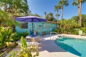 a blue house with an umbrella and a pool at Cabin with Boat Launch and Pool Access in Okeechobee in Okeechobee