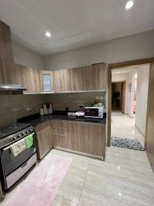 a kitchen with wooden cabinets and a microwave at Luxurious 2BHK apartment muscat bousher in Muscat