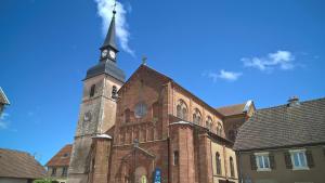 a church with a tower with a clock on it at Spacieux 61 metres carré tout confort in Grandvillars
