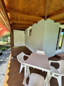 a patio with a table and chairs on a deck at Maisonnette de campagne, Sofaia à 5 min in Sainte-Rose