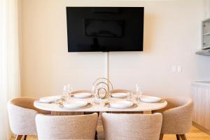 a dining room table with chairs and a tv on the wall at Distrito Morelos by Andiani Travel in Puerto Morelos
