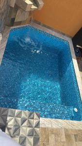 une piscine bleue avec un fond carrelé dans l'établissement Casa Raio de Luz, à Itanhaém