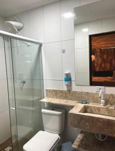 a bathroom with a toilet and a sink and a shower at Suítes Ventos e Velas Praia in Pôrto de Pedras