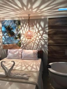 a bedroom with a bed and a bath tub and a chandelier at Suítes Ventos e Velas Praia in Pôrto de Pedras +4 photos