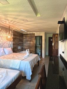 a bedroom with two beds and a flat screen tv at Suítes Ventos e Velas Praia in Pôrto de Pedras