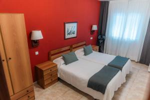 a bedroom with a bed and a red wall at Hostal Regina in Blanes