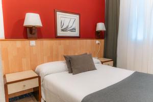 a bedroom with two beds and a red wall at Hostal Regina in Blanes