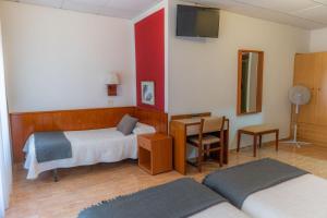 a bedroom with two beds and a desk and a television at Hostal Regina in Blanes