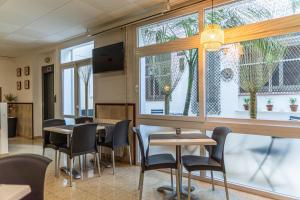 a dining room with tables and chairs and windows at Hostal Regina in Blanes