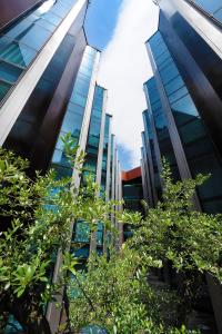 un edificio de cristal alto con árboles delante de él en Fènix Hotel en Andorra la Vella