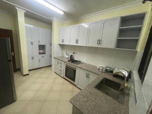 a kitchen with white cabinets and a counter top at Arusha Serenity Apartment in Arusha