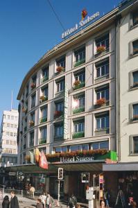 ein Hotelgebäude mit Leuten, die davor laufen in der Unterkunft Hotel Suisse in Genf